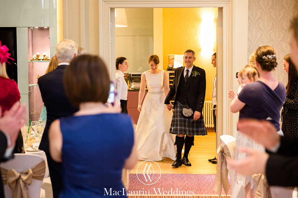 a bride and groom entering wedding breakfast at the rivers suite napier with guests clapping
