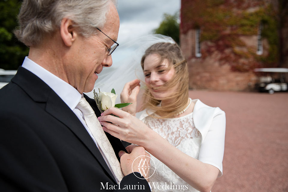 a happy bride adjusting her fathers&nbsp; buttonhole dalhousie castle scotland