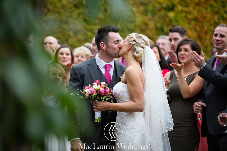 The bride and groom have a kiss in front of the guests