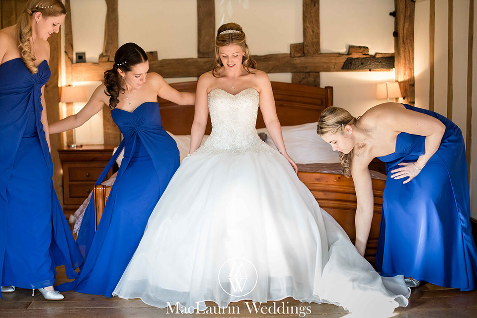 bride is getting helped by her bridesmaids