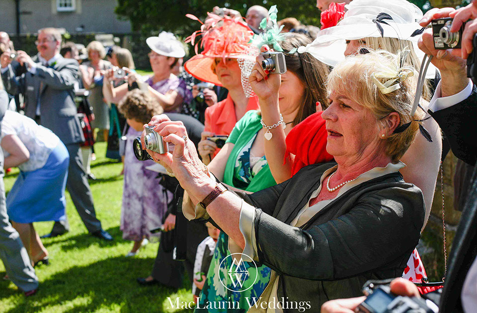 wedding guests taking photographs of the bride and groom