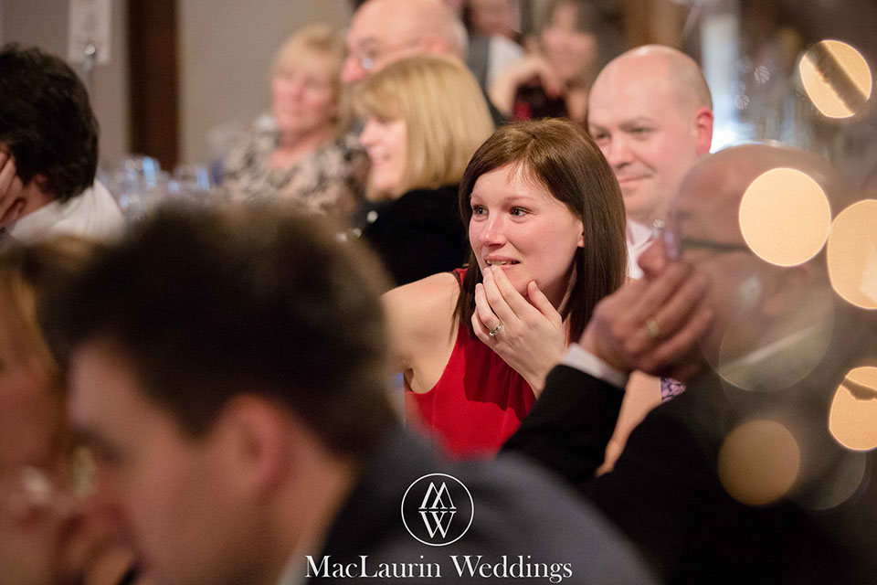 a wedding guest listening intently to the speeches at the reception