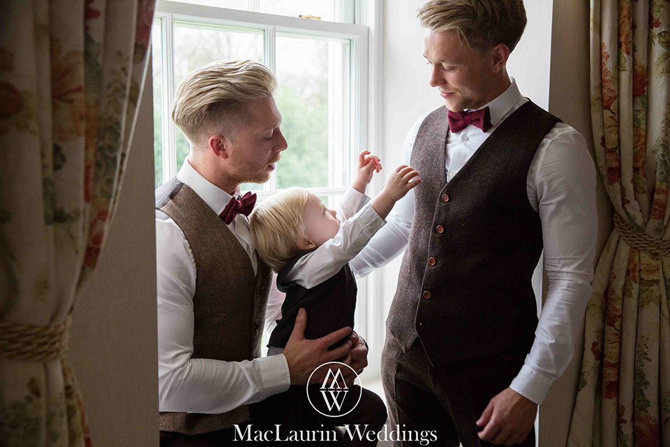 a groom and his brother by the window with a young boy