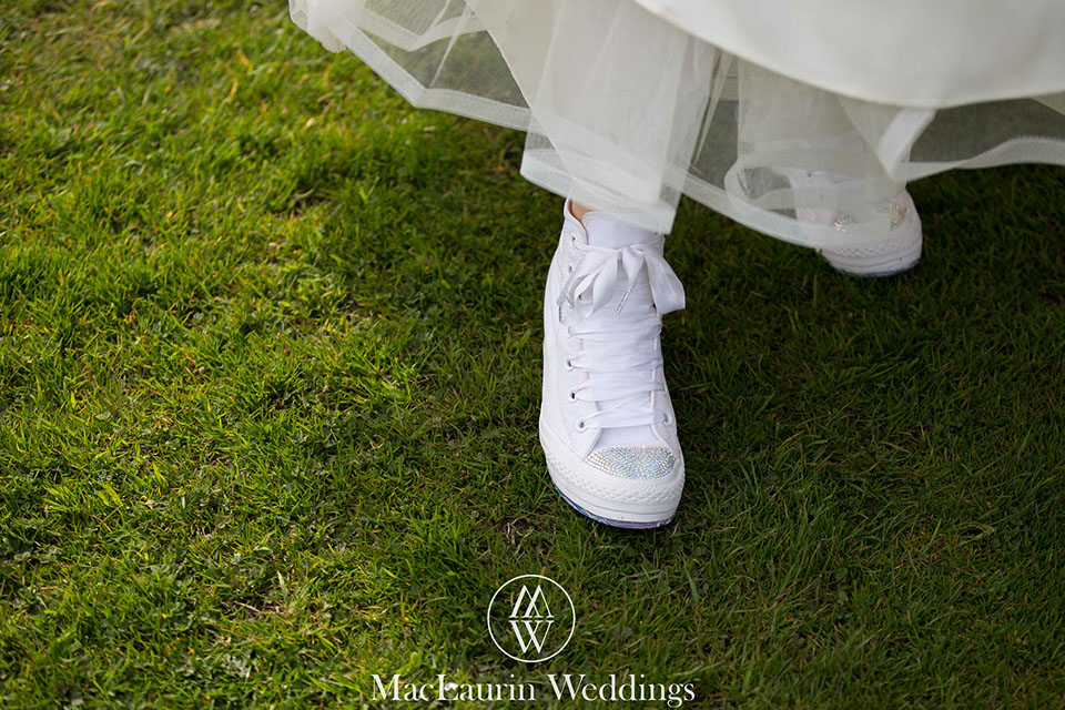 a bride is wearing sparkly converse on grass 
