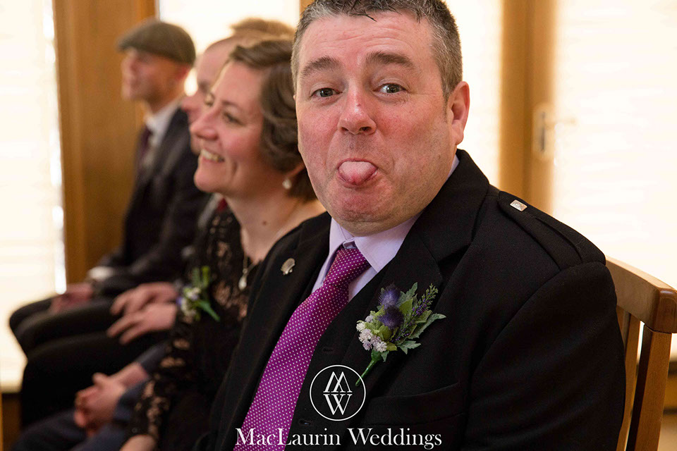 a funny wedding guest sticks out his tongue wile getting photographed